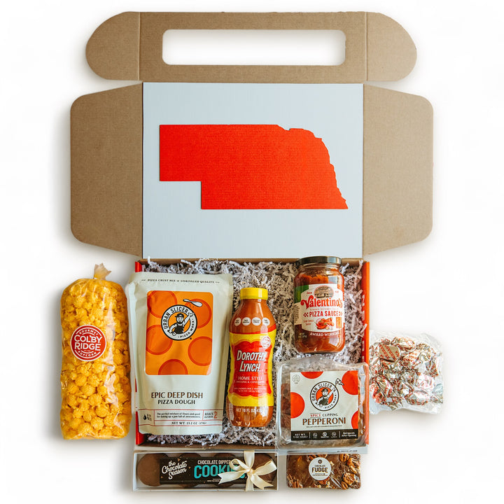 Nebraska pizza night gift box open with various food items inside including pizza dough, pizza sauce, popcorn, pepperoni, salad dressing, mint meltaways, chocolate covered Oreos, and walnut fudge.